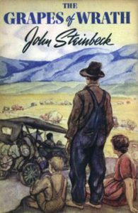 The Grapes of Wrath book cover with standing man in overalls with woman and son sitting by his side facing hills.