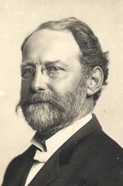 Bust-length portrait of a bearded Pardee wearing glasses.