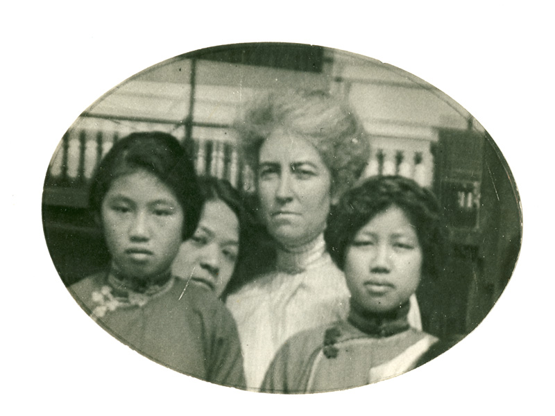 Shows three women, group of children sitting on steps.