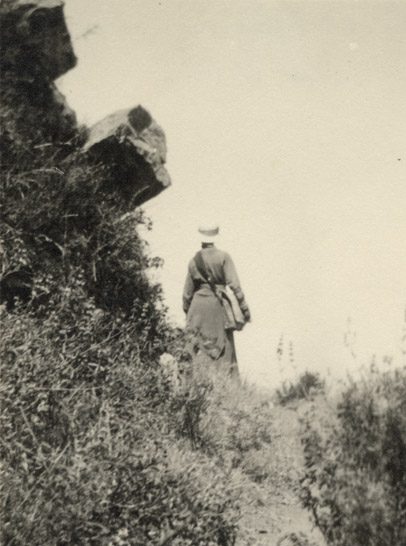 Ann Hadden walks up a hillside trail with book bag