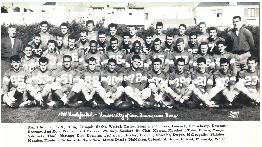 A black and white photograph of a college football team posing for a team portrait in uniform.