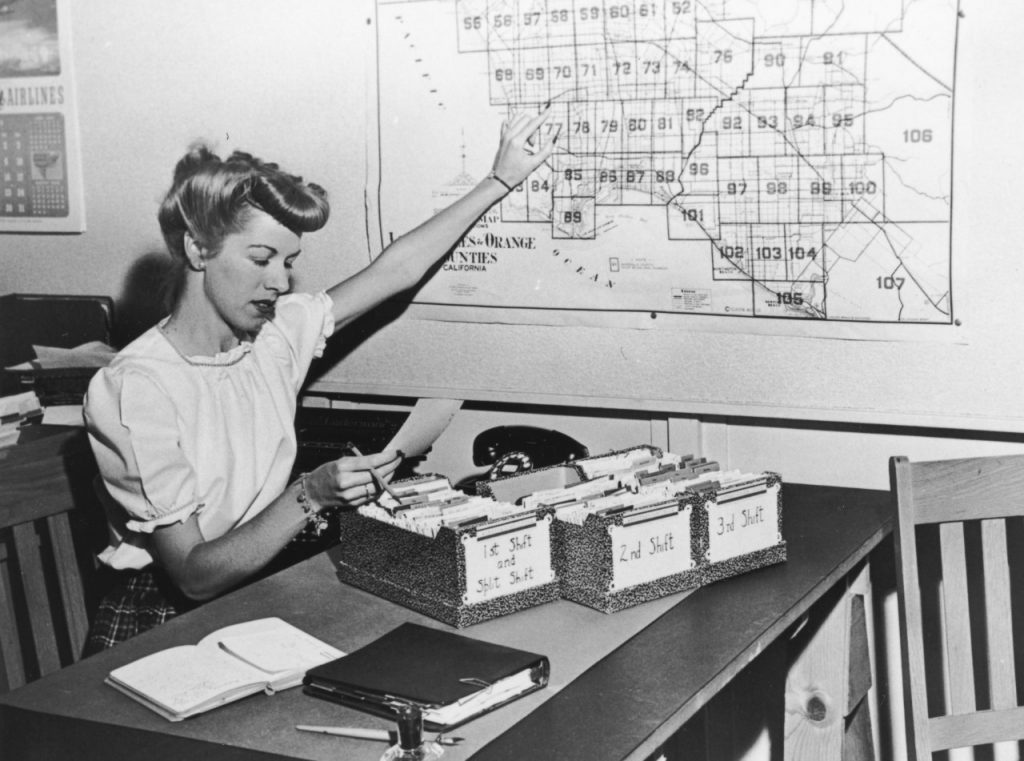 Housing Bureau clerk matching employee shifts to a transportation area map, c. 1941-45.
